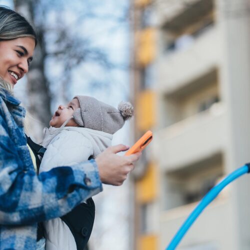 Mom charging EV with baby