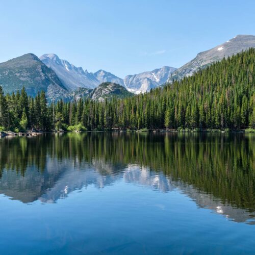mountains surrounding forest and lake