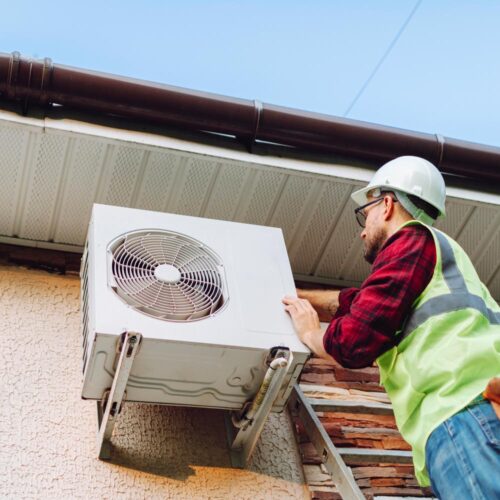 Technician in uniform repairing heat pump